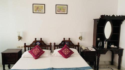 a bedroom with a bed with red and white pillows at Kotra Haveli A Boutique Hotel by Lake Pichola in Udaipur