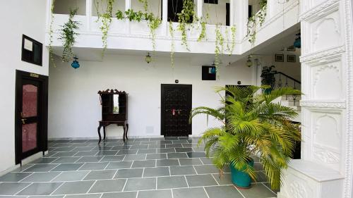 a hallway with white walls and a floor with plants at Kotra Haveli A Boutique Hotel by Lake Pichola in Udaipur