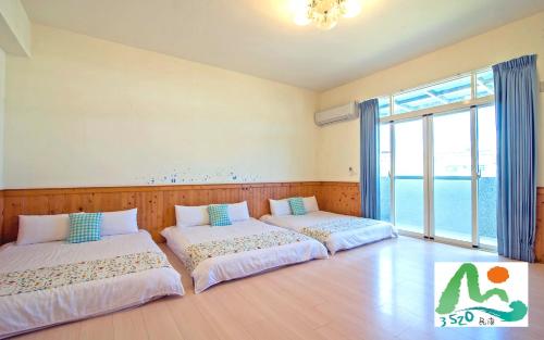 two beds in a room with a large window at 3520 Homestay in Taitung City