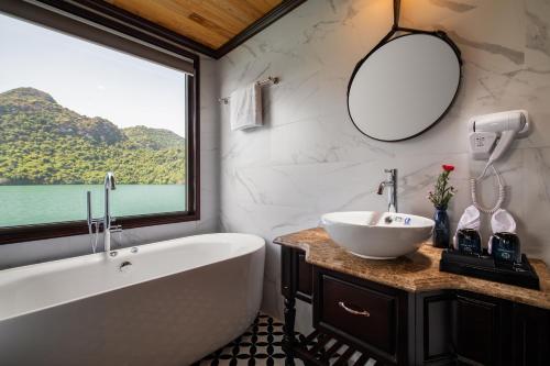 baño con bañera, lavabo y ventana en La Casta Regal Cruise, en Ha Long