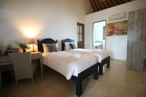 a bedroom with two beds and a desk and a table at OK Divers Resort & Spa in Padangbai