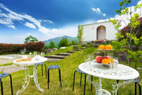 two tables and chairs with fruit on top of a yard at Alps Lodge & Spa in Hokuto