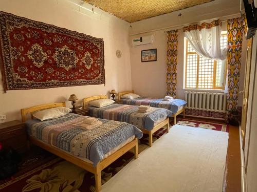 a room with three beds and a window at Guest House Khiva ,, BOYJON OTA " in Khiva