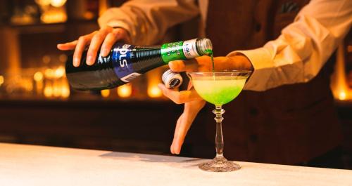 a man pouring a green drink into a martini glass at HOTEL SANSUI NAHA Ryukyu Onsen Naminoue-No-Yu in Naha