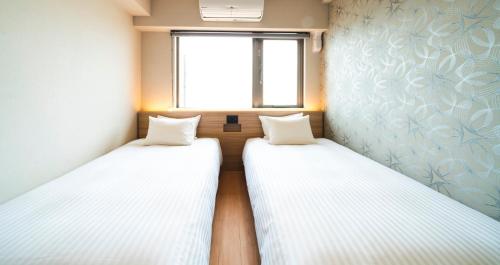 two beds in a small room with a window at HOTEL SANSUI NAHA Ryukyu Onsen Naminoue-No-Yu in Naha