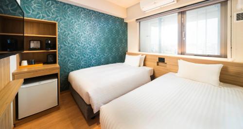 two beds in a small room with a window at HOTEL SANSUI NAHA Ryukyu Onsen Naminoue-No-Yu in Naha