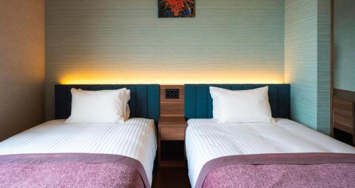 two beds sitting next to each other in a room at HOTEL SANSUI NAHA Ryukyu Onsen Naminoue-No-Yu in Naha