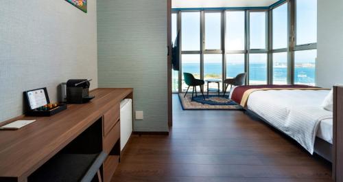 a hotel room with a bed and a desk and chairs at HOTEL SANSUI NAHA Ryukyu Onsen Naminoue-No-Yu in Naha
