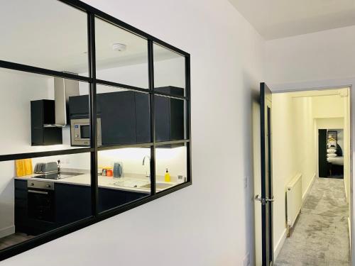 a kitchen with black cabinets and a mirror on the wall at Eden Retreats Serviced Apartments in Morecambe