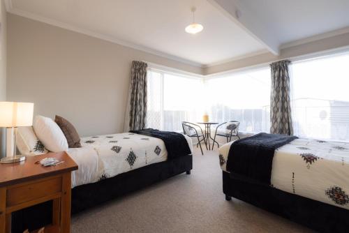 a bedroom with two beds and a table and a window at Oamaru Backpackers in Oamaru