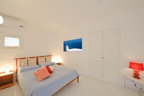 a white bedroom with a bed and a red lamp at Beth in Praiano