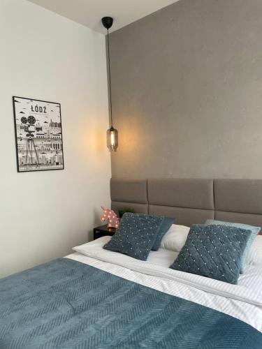a bedroom with a bed with blue and white pillows at BOOGIE Home Kamienica Łódzka in Łódź