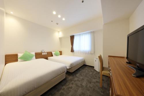 um quarto de hotel com duas camas e uma televisão de ecrã plano em Cityroute Hotel em Osaka