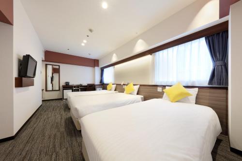 a hotel room with two beds and a tv at Cityroute Hotel in Osaka