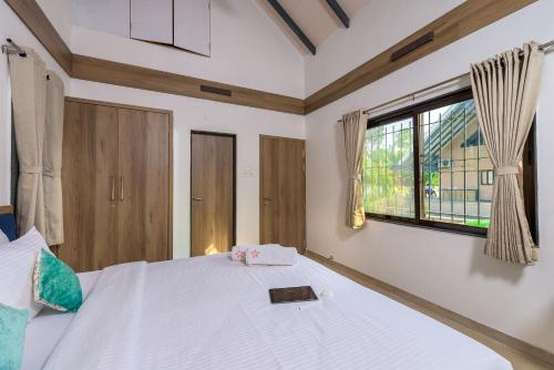 a bedroom with a large white bed with a window at SaffronStays Eden, Nashik - pet-friendly villa with pool, jacuzzi & grape farm in Nashik