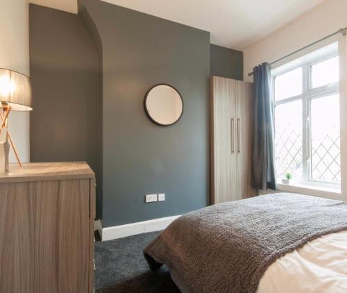 a bedroom with a bed and a mirror on the wall at Centralized Private 4 BR House at Hanley with Free Parking in Etruria