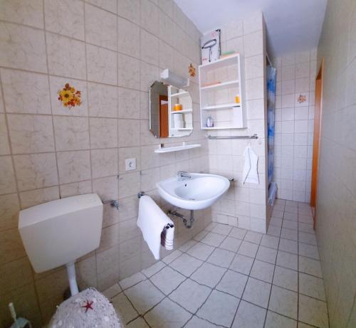 ein weißes Bad mit einem Waschbecken und einem WC in der Unterkunft Ferienwohnung Nr 3, Lechbruck-Gründl, Allgäu in Prem