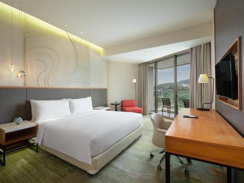a bedroom with a bed and a desk and a computer at Radisson Golf & Convention Center Batam in Batam Center