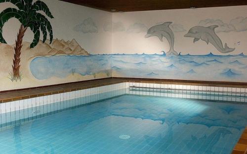 上斯陶芬的住宿－Appartement Nr 19, Alpenappartementhaus, Oberstaufen-Steibis, Allgäu，墙上画有海豚的游泳池