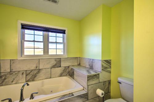 a bathroom with a tub and a window and a toilet at Harrisonburg Retreat with Hot Tub about 2 Mi to JMU in Harrisonburg