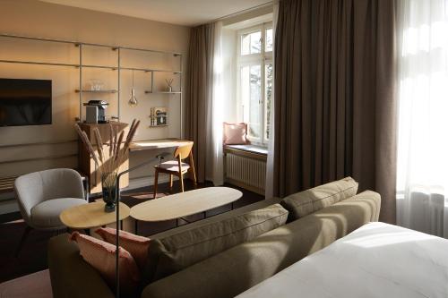 ein Wohnzimmer mit einem Sofa und einem Esszimmer in der Unterkunft Sorell Hotel Zürichberg in Zürich