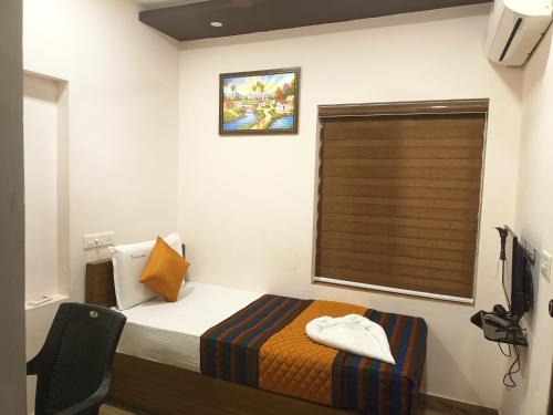 a small bedroom with a bed and a window at Majestic Inn in Trivandrum
