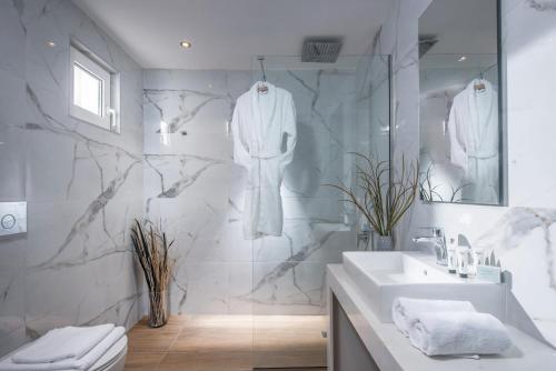 W białej łazience znajduje się umywalka i lustro. w obiekcie Alexander House Hotel w mieście Agia Pelagia