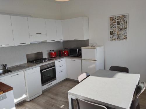 a kitchen with white cabinets and a white table and a counter at Viewpoint Cannero Apartment in Cannero Riviera