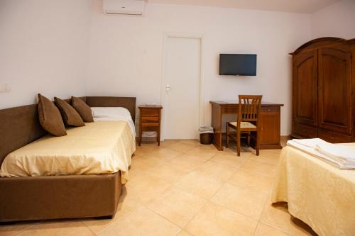 a bedroom with a bed and a desk and a television at Il Carmine Dimora Storica in Erice