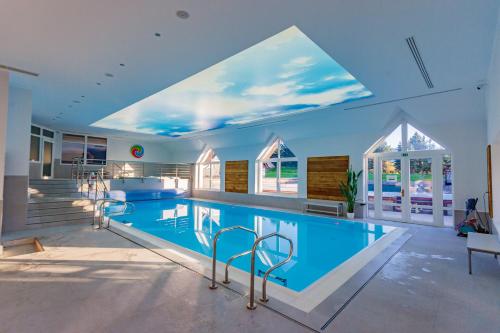 a large swimming pool with chairs around it at Oravský Háj Garden Hotel & Resort in Trstená