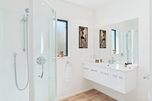 ein weißes Bad mit einer Dusche und einem Waschbecken in der Unterkunft Town Centre Location with Stunning View - Unit 1 in Queenstown