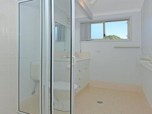 a bathroom with a toilet and a glass shower at Sealark in Callala Bay