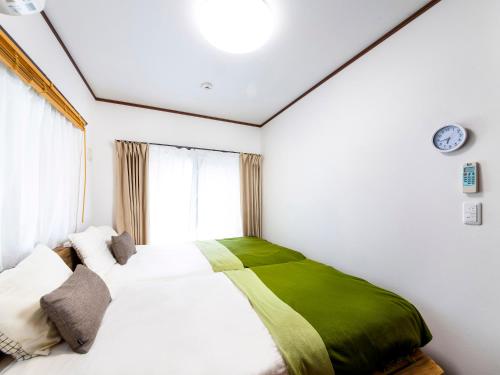 sypialnia z łóżkiem z zielonym kocem w obiekcie Sea Stay Okinawa w mieście Onna