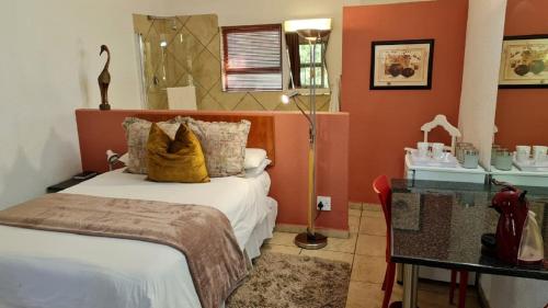 a bedroom with a bed and a desk with a lamp at St Michelle Guest Lodge & Hydro Retreat in Alberton