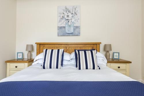 a bed with two striped pillows and a vase of flowers at Ropemaker’s Cottage in Ollerton