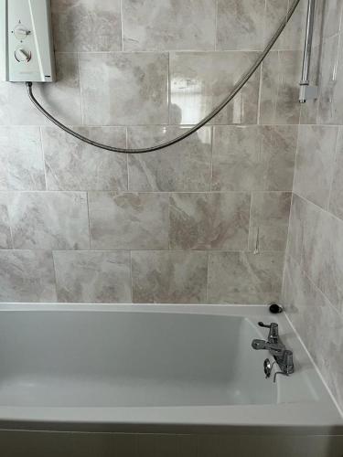 a bathroom with a bath tub with a sink at Milnrow Road - Spacious 3 bed house 