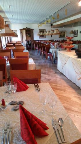 a restaurant with tables and chairs with red napkins at Hotel Villa Emilia in Ortisei