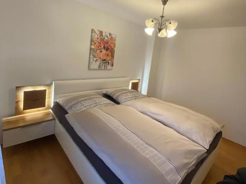 a large bed in a bedroom with a chandelier at Ferienwohnung Leo in Bad Endorf