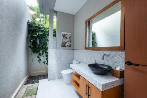 a bathroom with a black sink and a plant at THE COINS VILLA SEMINYAK in Seminyak