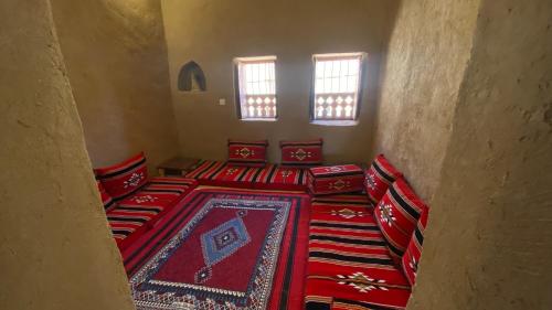 a room with red pillows and a red carpet at Alqalah Inn in Al Ḩamrāʼ