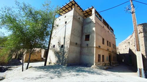 an old building with a tree in front of it at Alqalah Inn in Al Ḩamrāʼ