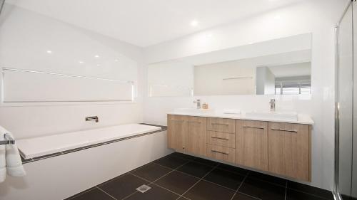 a bathroom with two sinks and a tub and a mirror at The Palms - Lennox Head in Lennox Head