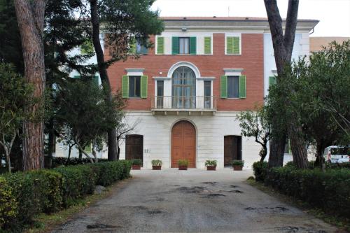 a large house with green shutters and a driveway at Ostello e Camere Private Prima Luce Foresteria in Giulianova