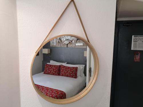 a mirror on a wall with a bed with red pillows at Hotel Boréal Nice in Nice