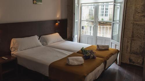 1 dormitorio con 1 cama con 2 toallas y una ventana en Pensión A Casa do Peregrino, en Santiago de Compostela