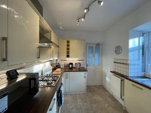 a kitchen with white cabinets and a stove top oven at Luxury Beds Parking 2 Bathrooms 3 Large Bedrooms Nice Area in Morecambe