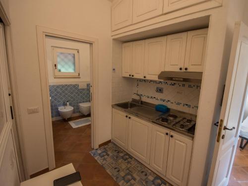 La cuisine est équipée de placards blancs, d'un lavabo et de toilettes. dans l'établissement Villetta Il Maestrale, à Palau