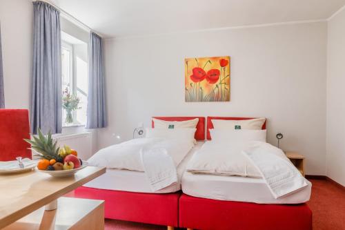 a bedroom with a red and white bed and a table at Apartmenthotel Weilburg in Weilburg