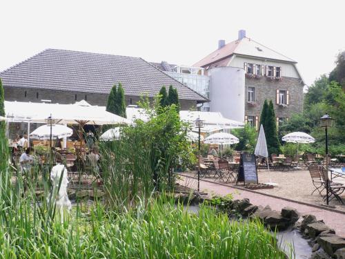a restaurant with tables and umbrellas in front of a building at Landhaus Grum in Hattingen