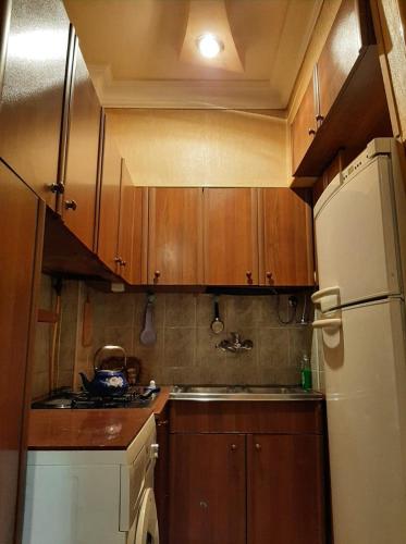 a kitchen with wooden cabinets and a white refrigerator at Квартира в центре in Yerevan
